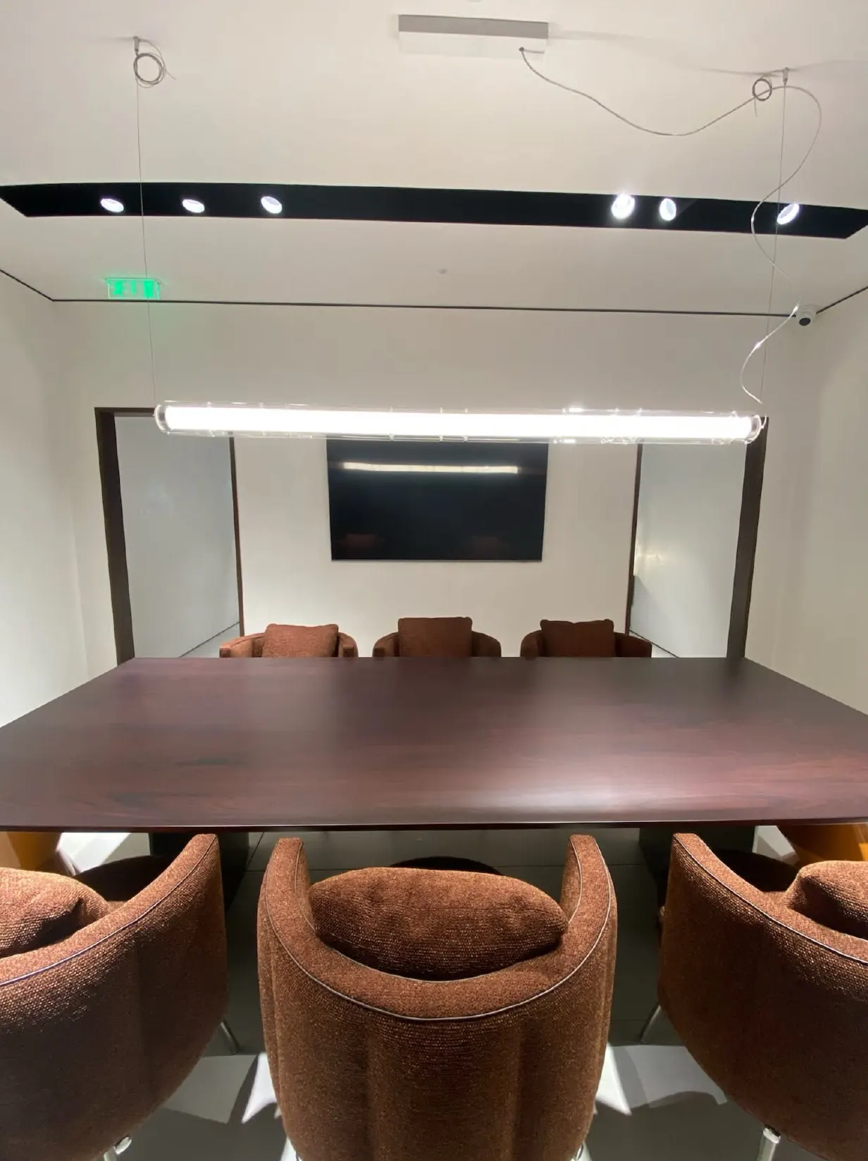 Sala de reuniões com iluminação linear preta e paredes em marmorino