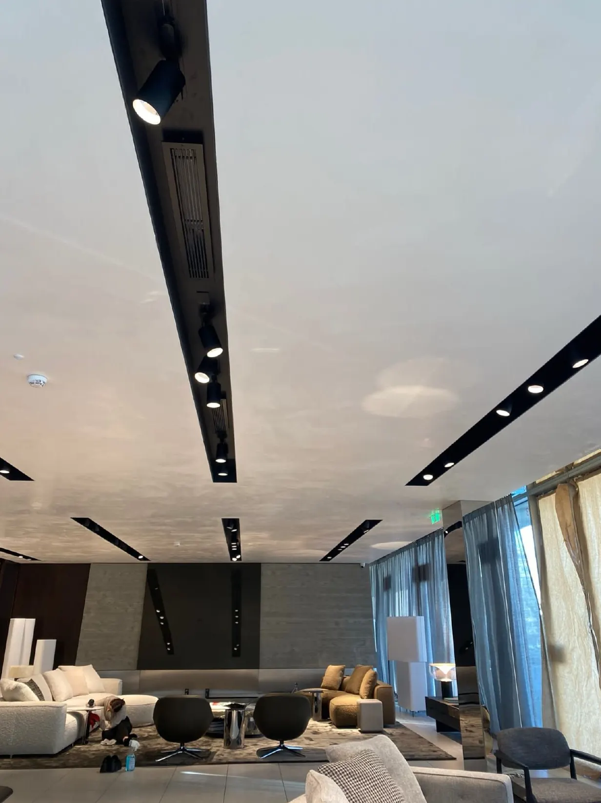 Sala ampla com tetos de calhas pretas e paredes revestidas em marmorino claro