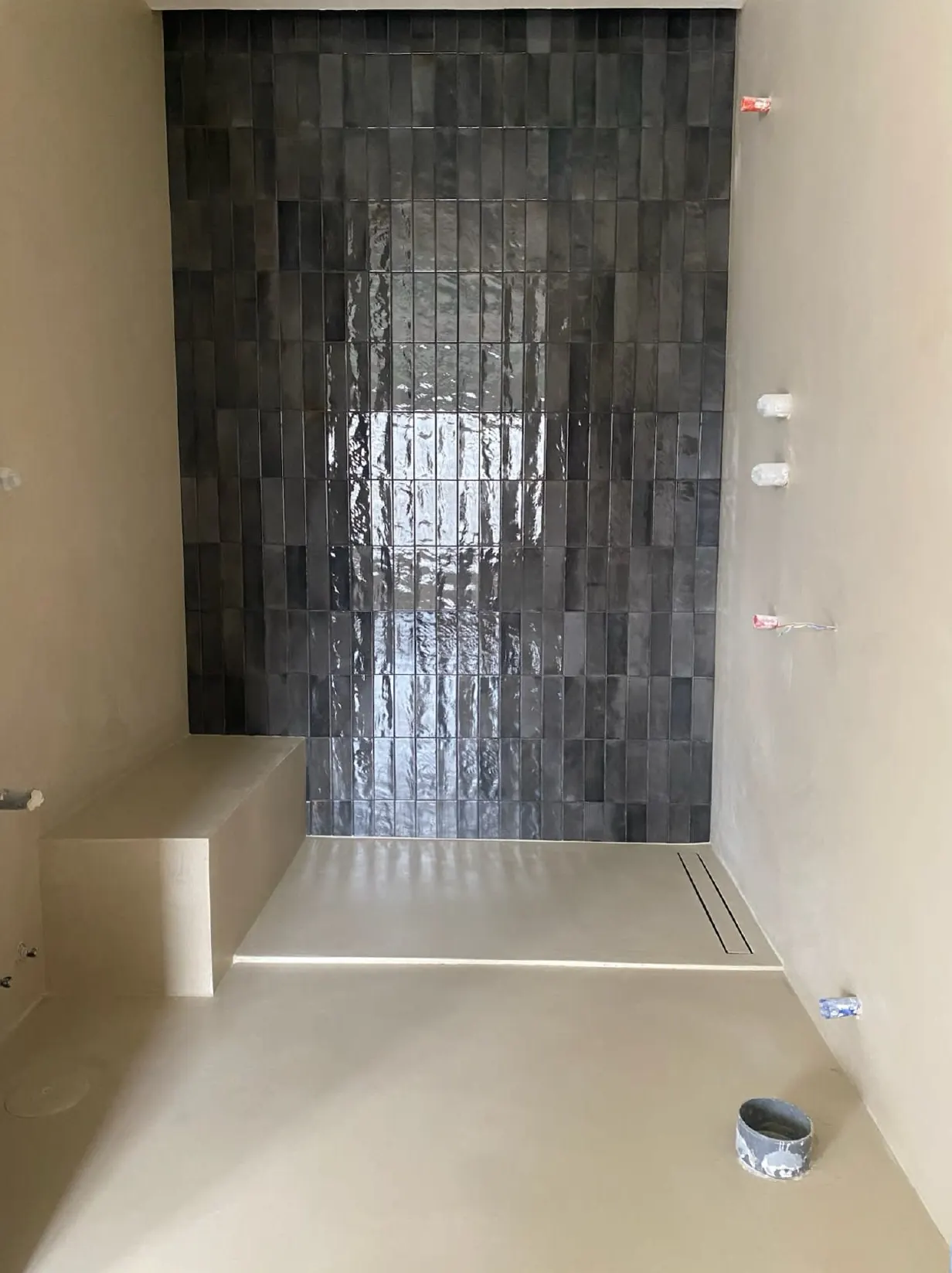Duche com parede de azulejo escuro e base em microcimento claro