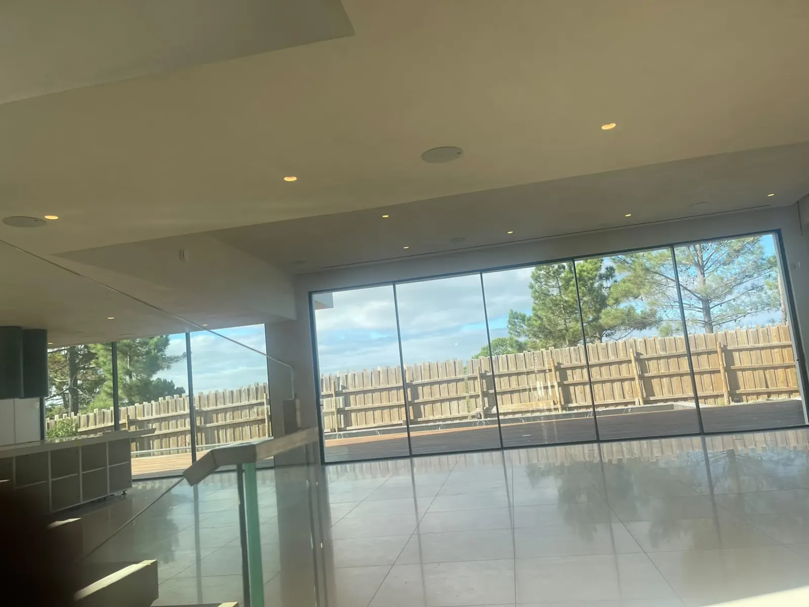 Sala com pavimento contínuo claro e janela panorâmica sobre o pinhal