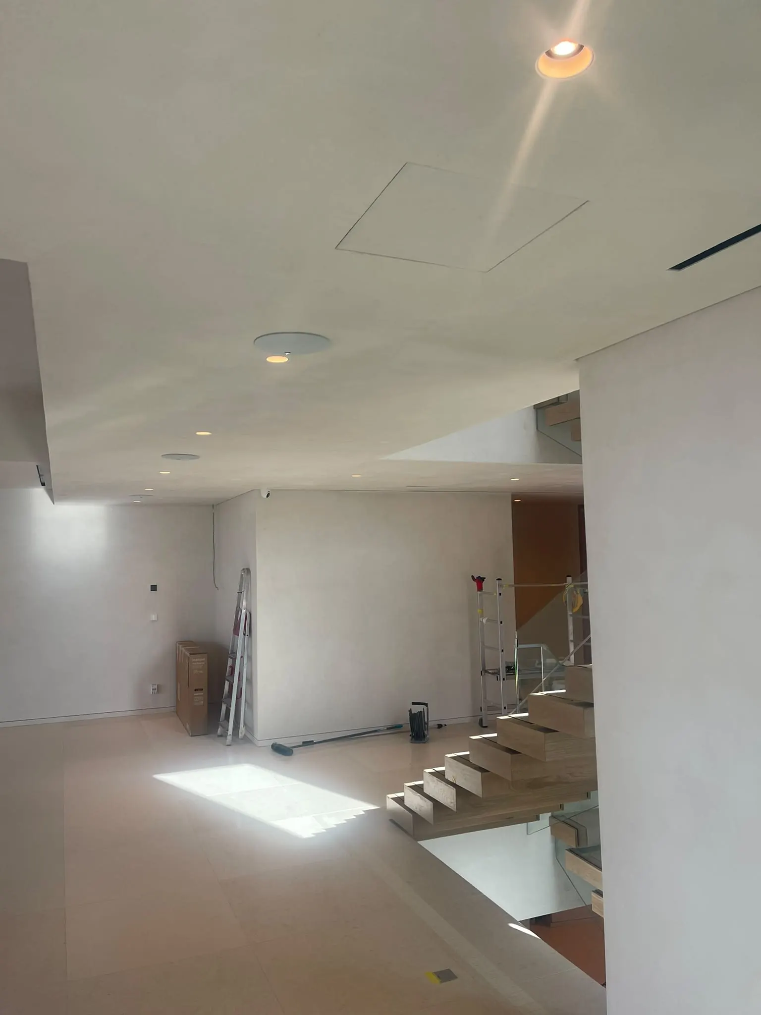 Sala com escada em vidro e pavimento contínuo claro
