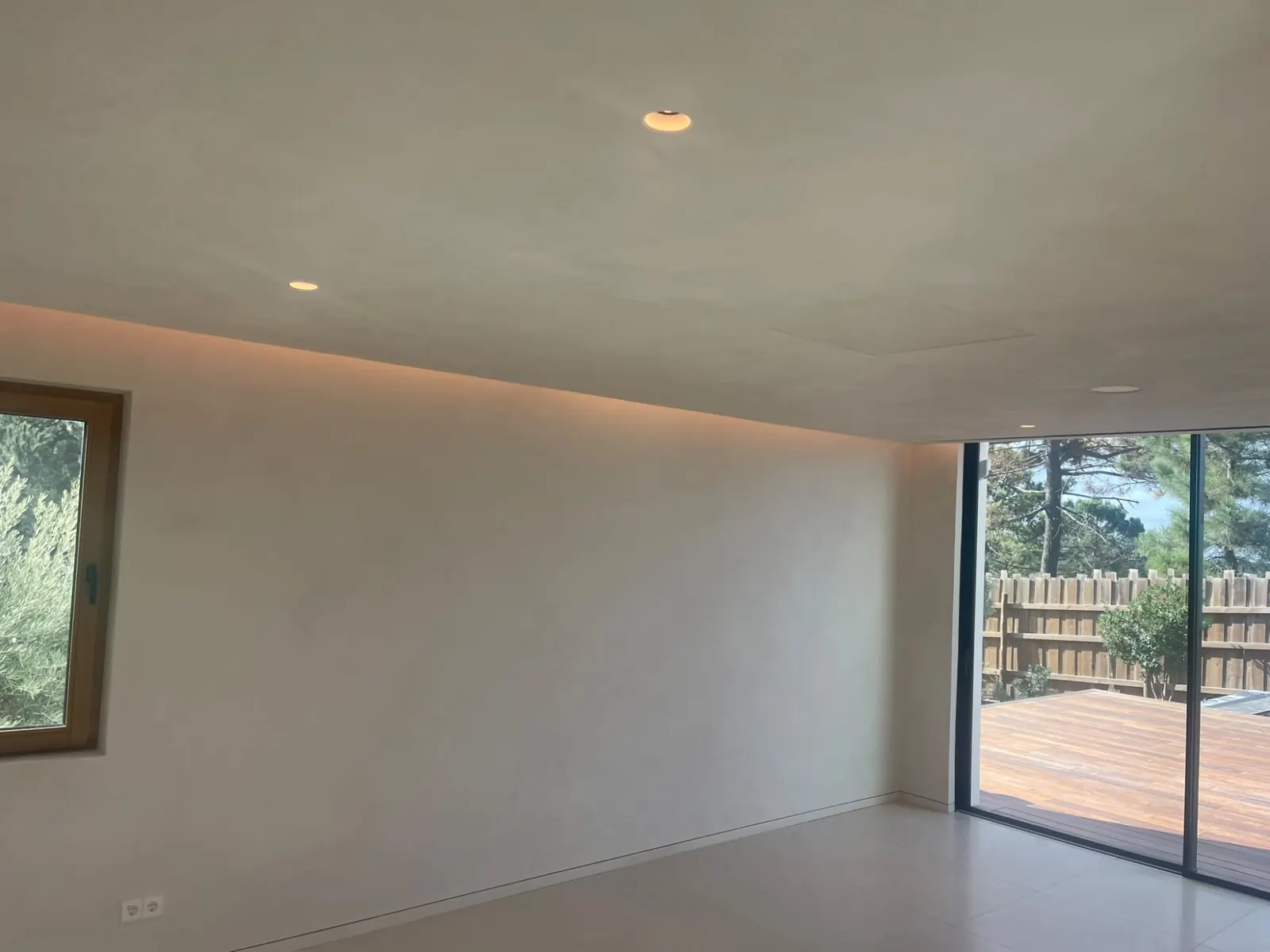 Sala com sanca iluminada e janela para o deque de madeira
