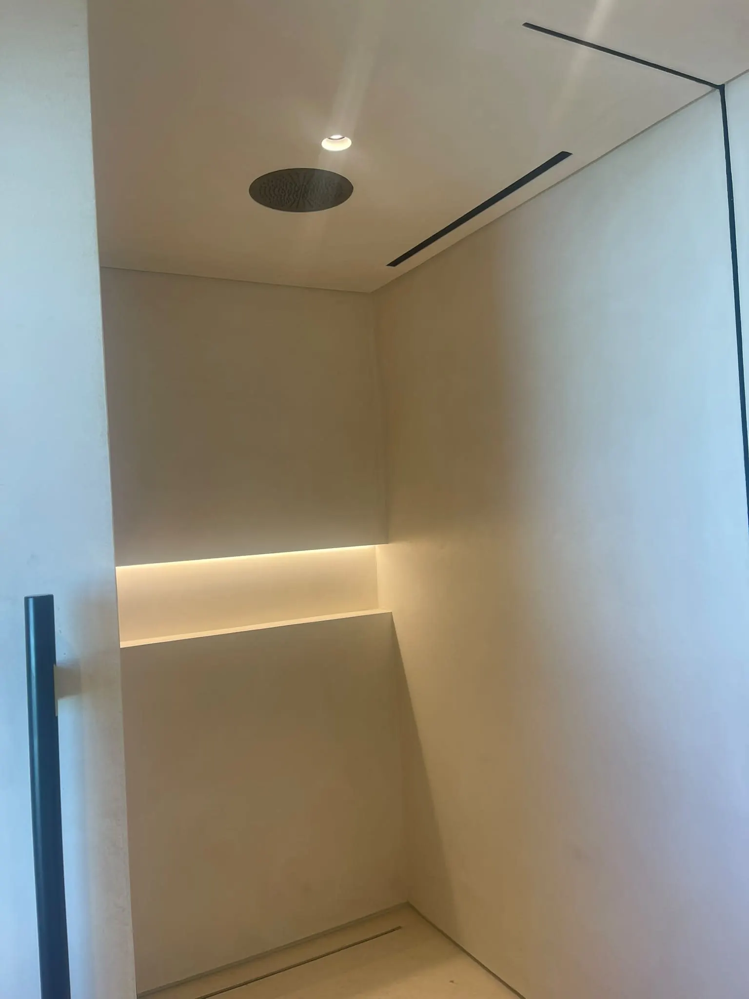 Duche com nicho iluminado e paredes contínuas claras