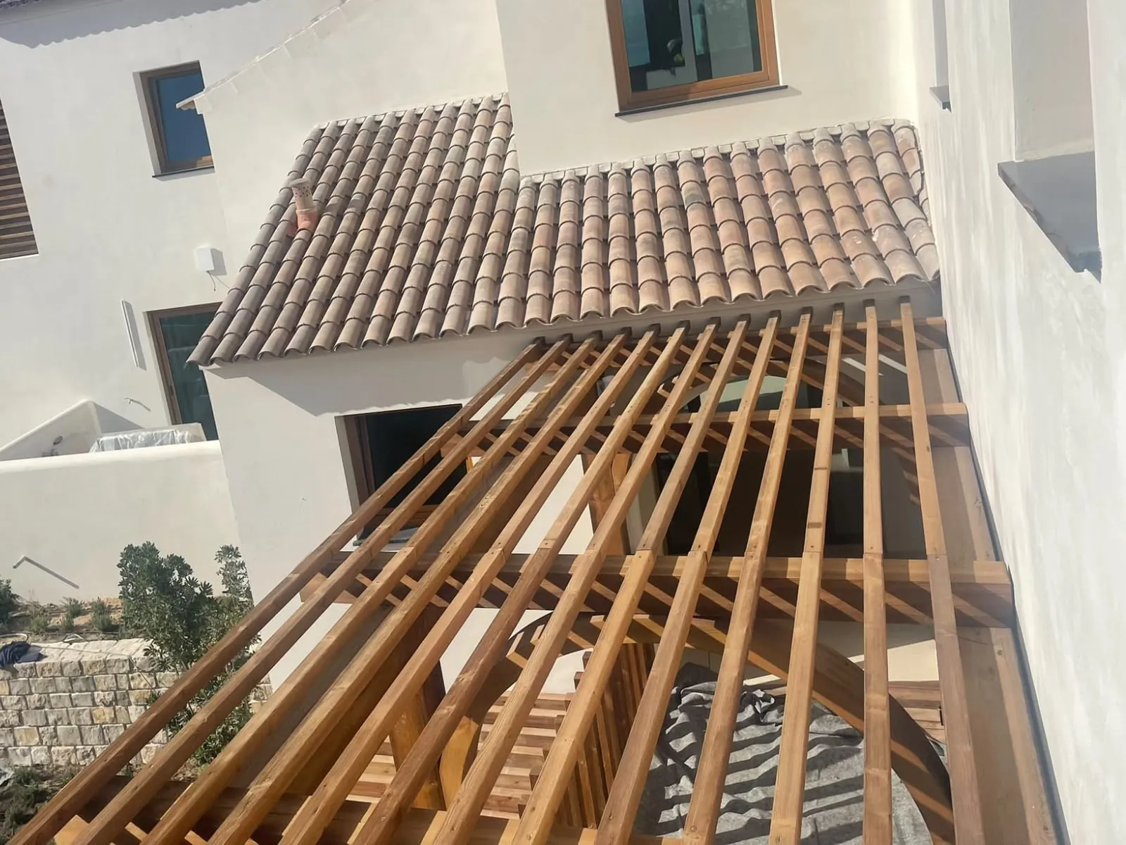 Moradia branca com telhado de telha e pérgula de madeira