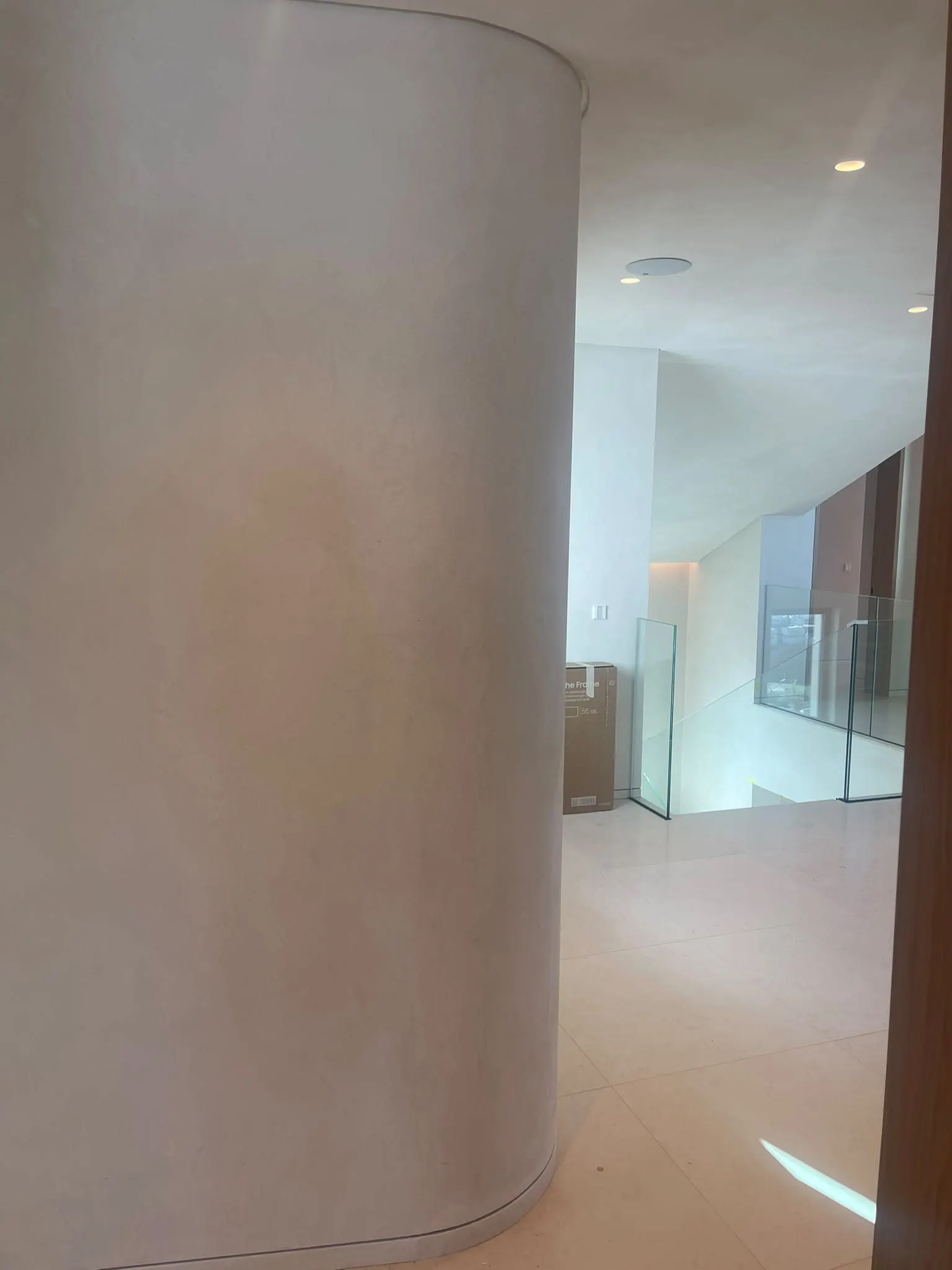 Parede curva revestida em tom cinza claro, sem juntas