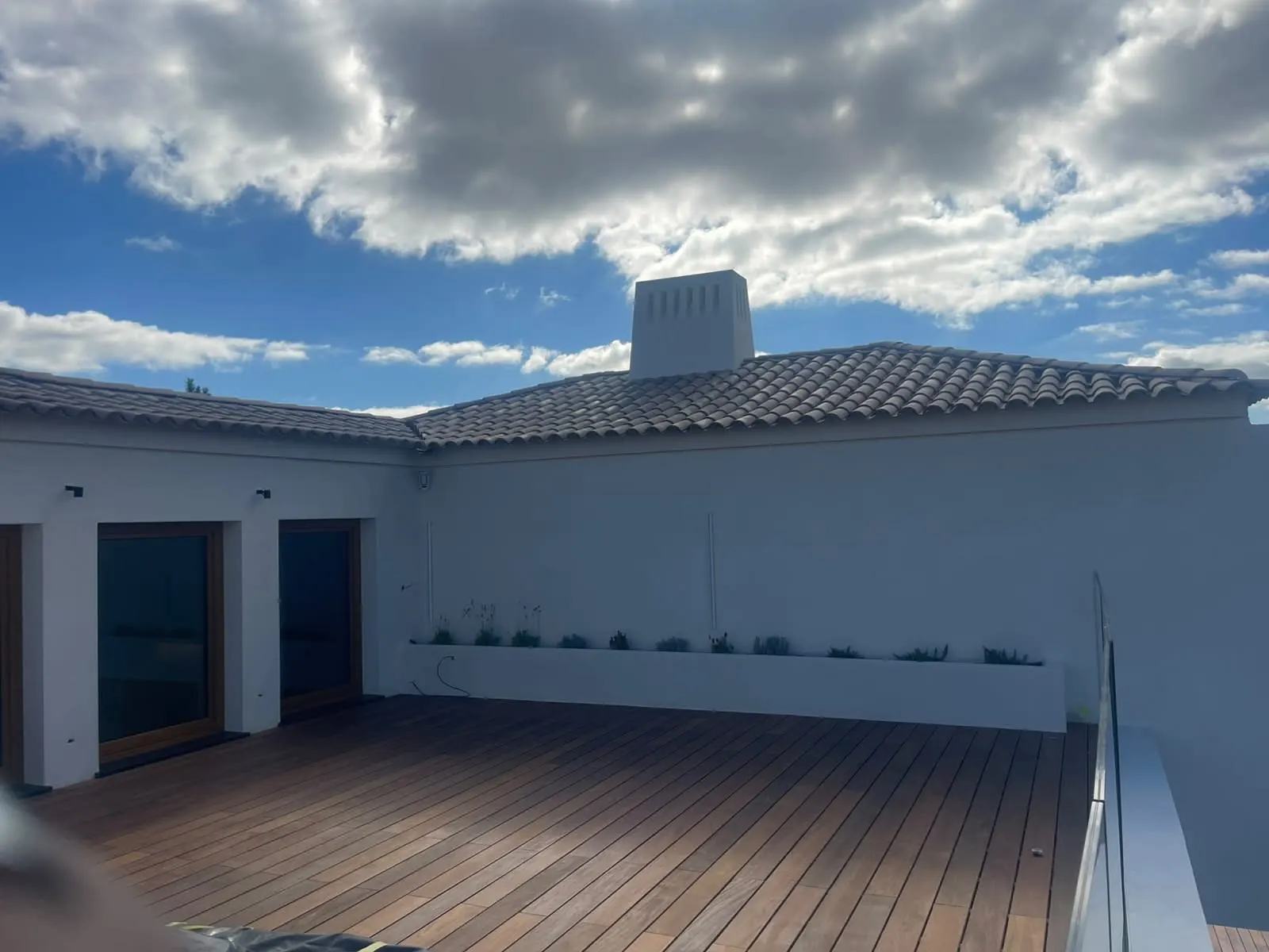 Pátio com deque de madeira e floreiras sob céu azul